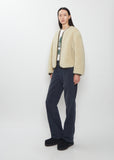 Full view of the Visvim Liner Down Jacket in ivory worn with dark trousers.
