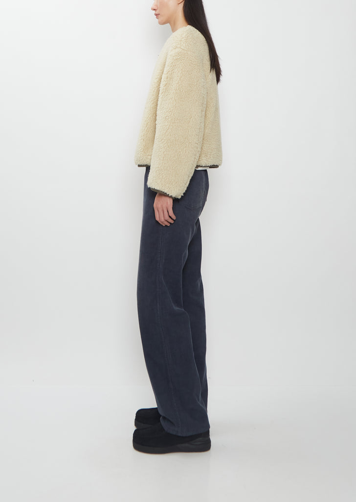 Side view of the Visvim Liner Down Jacket in ivory worn with dark trousers.