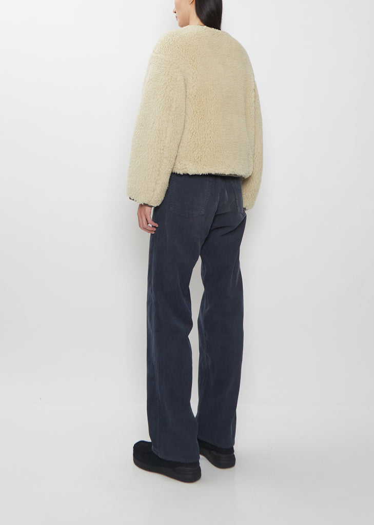 Rear view of a model wearing the Visvim Liner Down Jacket in Ivory with dark pants.