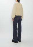 Rear view of a model wearing the Visvim Liner Down Jacket in Ivory with dark pants.