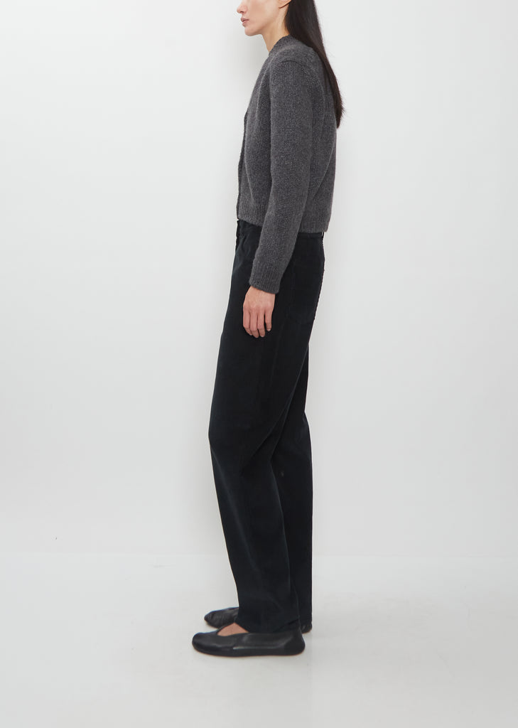 Side view of Weiling wearing The Row Duvan cotton corduroy pants in faded black.