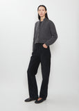 A full-length view of the Duvan Cotton Corduroy Pant in faded black worn with a grey cardigan.