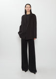 Front view of The Row Cinna Cashmere Jacket in dark brown worn with black trousers.