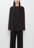 Front view of a model wearing The Row dark brown Cinna Cashmere Jacket and black trousers.