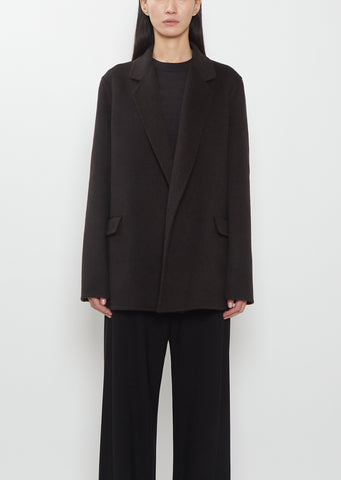Front view of a model wearing The Row dark brown Cinna Cashmere Jacket and black trousers.