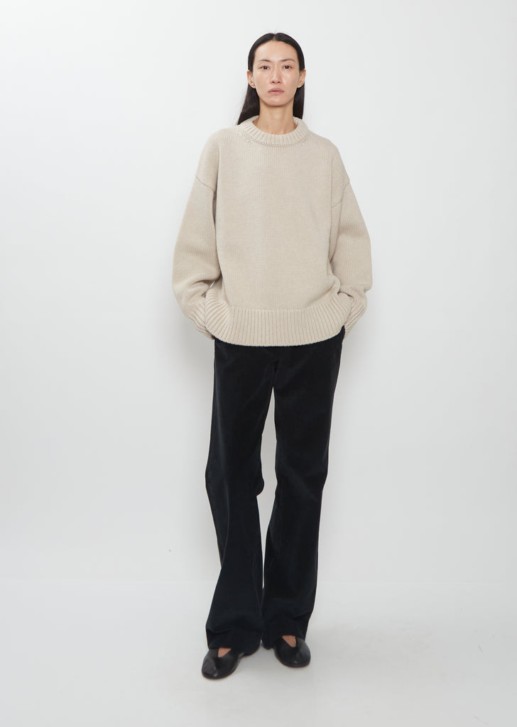 Full view of the Ophelia Wool Cashmere Top in sand beige with black trousers.