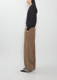 Side view of The Row Adler Cotton Corduroy Pant in faded sepia, worn with a black sweater.