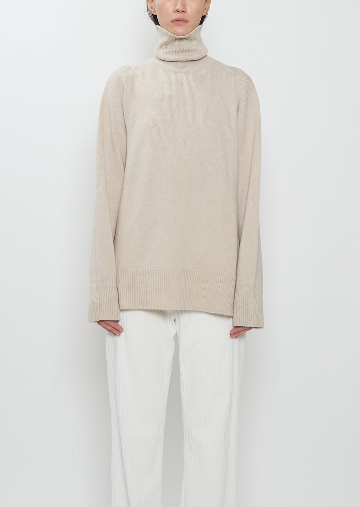 Front view of The Row Stepny Wool Cashmere Top in sand beige with a turtleneck.