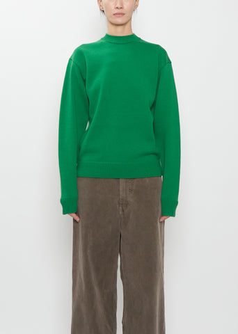 Front view of a model wearing the green Auralee super fine wool knit pullover and brown trousers.