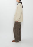 Side view of Weiling wearing the Auralee ivory Homespun Tweed Zip Blouson and brown trousers.