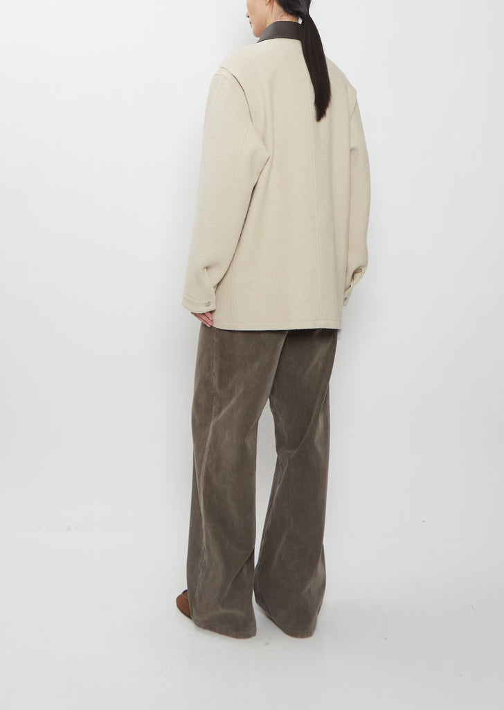 Rear view of the Auralee Homespun Tweed Zip Blouson in ivory beige, showing the relaxed fit and brown corduroy pants.