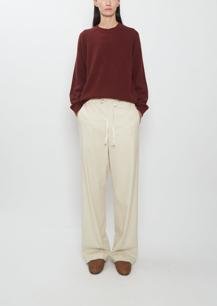 Front view of a model wearing Auralee Wool Fulling Flannel Drawstring Pants in top ivory.