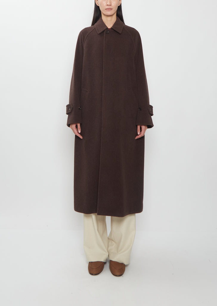 A person wearing a dark brown Super Fine Wool Mosser Soutien Collar Coat, light trousers, and brown shoes.