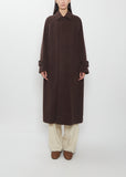 A person wearing a dark brown Super Fine Wool Mosser Soutien Collar Coat, light trousers, and brown shoes.