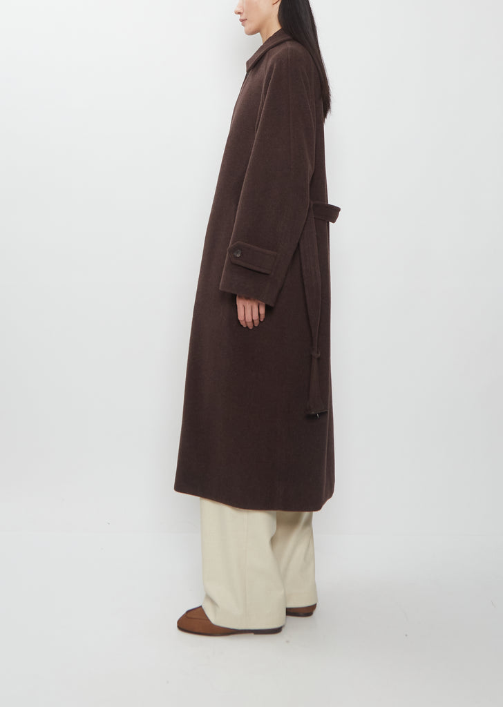 A person wears a dark brown Super Fine Wool Mosser Soutien Collar Coat with a belt over wide-leg trousers.