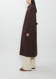 A person wears a dark brown Super Fine Wool Mosser Soutien Collar Coat with a belt over wide-leg trousers.