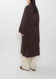 Person seen from behind wearing a long brown Super Fine Wool Mosser Soutien Collar Coat with wide cream-colored trousers.