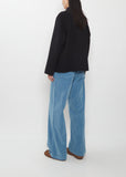 A person from behind wearing a black Super Fine Wool Melton Hand Sewn Blouson, wide-leg blue jeans, and brown shoes.