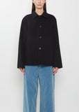 A person wearing a black Super Fine Wool Melton Hand Sewn Blouson and blue trousers.