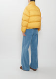 A person wearing a yellow Super Light Nylon Ripstop Down Blouson and blue wide-leg trousers.