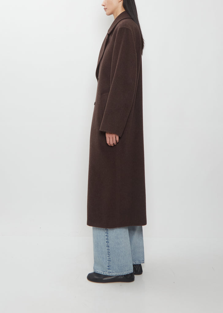 A person wearing a brown Super Fine Wool Mosser Double Breasted Coat over light-wash jeans.