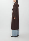 A person wearing a brown Super Fine Wool Mosser Double Breasted Coat over light-wash jeans.